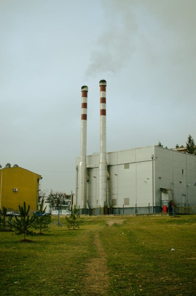 Two chimneys releasing smoke in an industrial area in Serbia, representing air pollution.