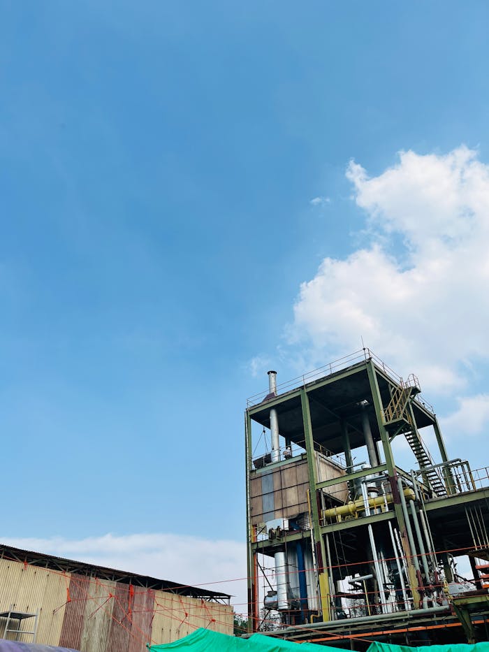 An industrial structure stands tall beneath a clear blue sky with scattered clouds.